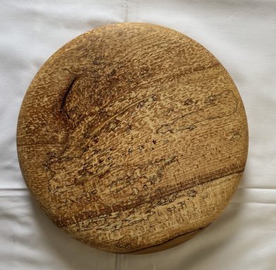 Round wooden board with a textured surface.