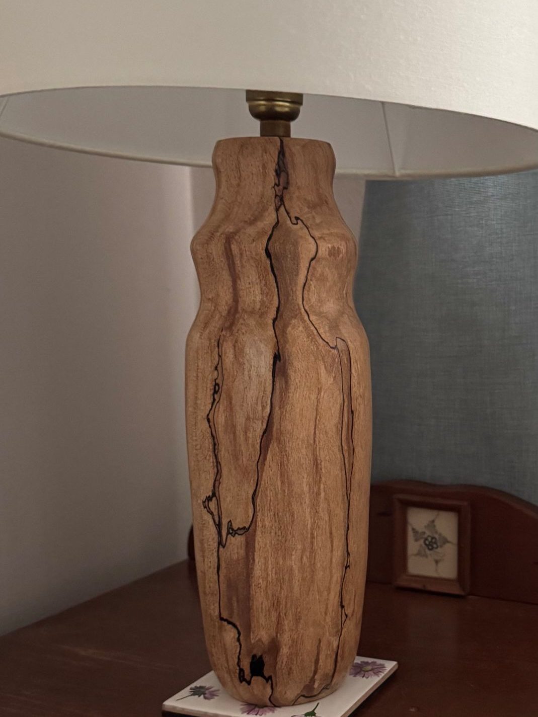 Wooden lamp base with a natural, textured finish and a white lampshade.