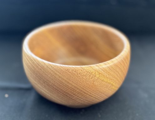 A smooth wooden bowl with a natural finish and rounded shape.