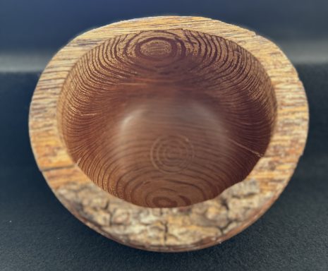 A rustic wooden bowl with visible grain patterns and a rounded, smooth interior.