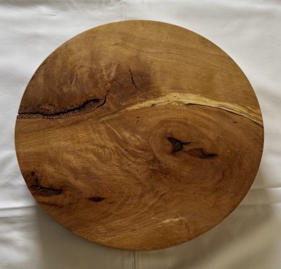 Round wooden platter with a smooth surface and natural grain patterns.