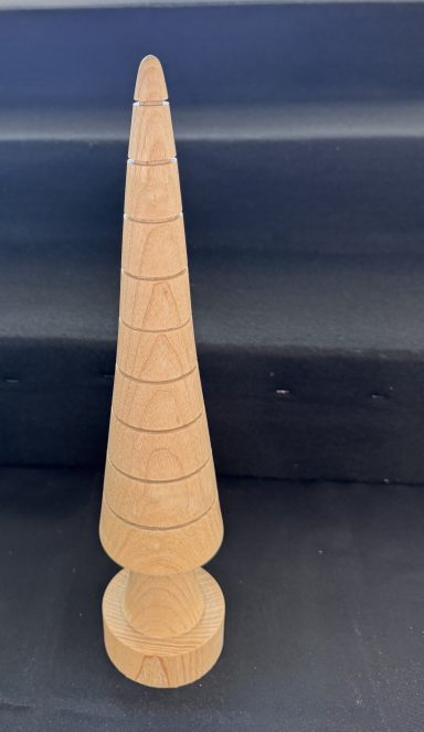 A tall, conical wooden sculpture with spiral grooves and a rounded base.