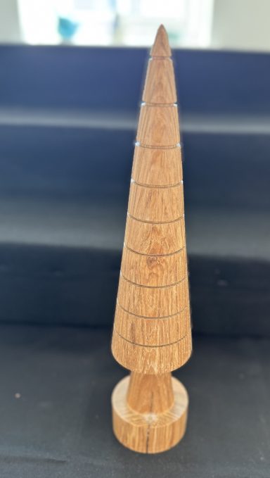 Wooden cone-shaped sculpture with a rounded base, featuring horizontal engraved lines.