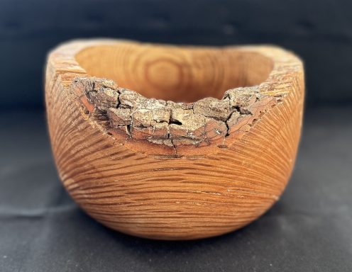 Wooden bowl with a natural, rough edge and textured surface.
