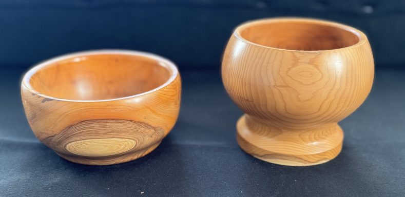 Two wooden bowls, one round and shallow, the other tall with a pedestal base.