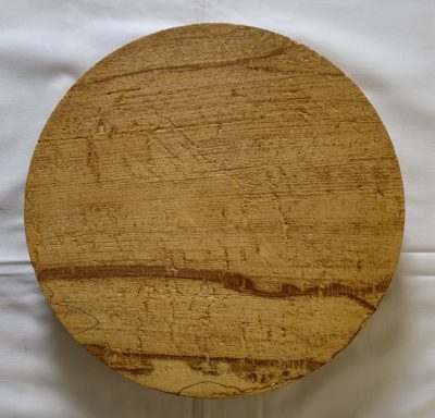 Round wooden board with a light brown finish and visible grain patterns.