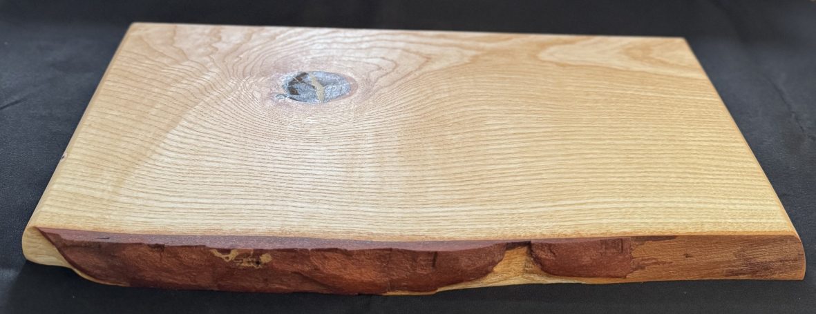 A wooden serving board with a smooth surface and natural edge detail.