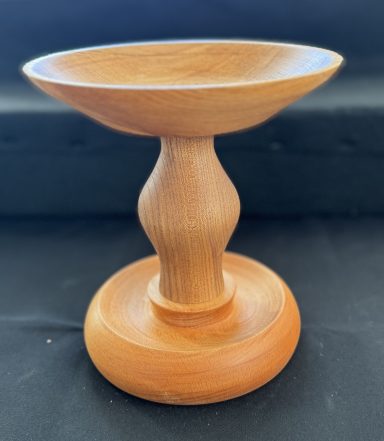 Wooden pedestal bowl with a smooth, rounded base and a flared, shallow dish.