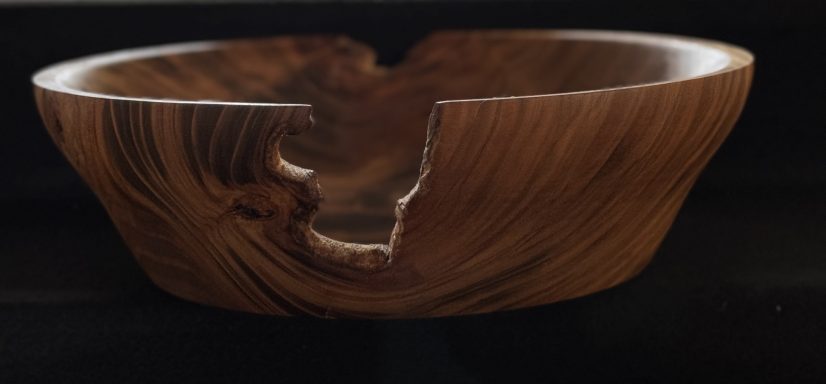 A handcrafted wooden bowl with a unique crack and smooth, polished surface.