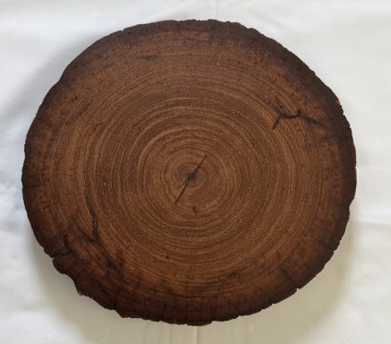 Round wooden slice with visible growth rings and a dark brown finish.