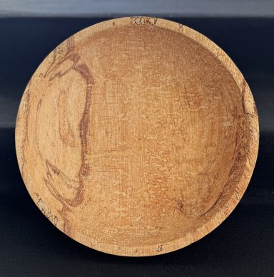A round wooden bowl with a smooth, light-coloured finish, showing natural wood grain.
