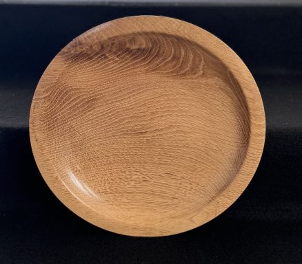 A smooth, circular wooden plate with a natural wood grain pattern.