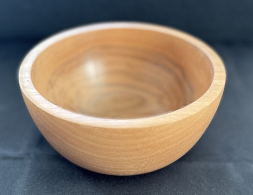 A smooth wooden bowl with a rounded base and a light finish.