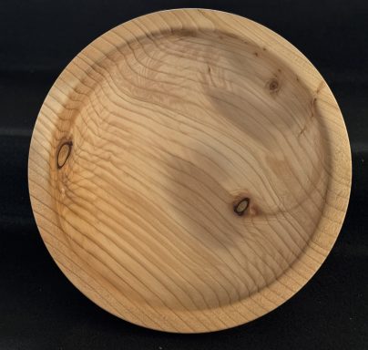 Round wooden plate with a smooth surface and natural grain patterns.