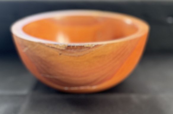 A smooth wooden bowl with a warm, orange-brown hue.