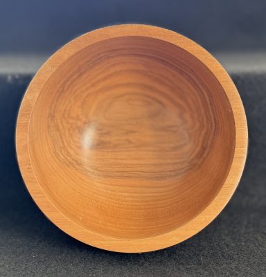 A smooth wooden bowl with a rich grain and a warm, natural finish.