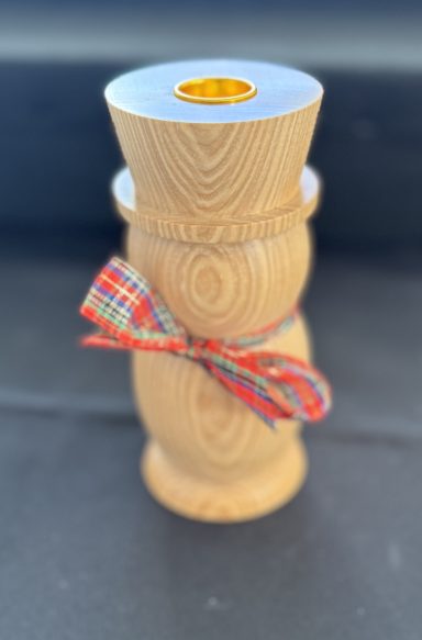 Wooden spice grinder with a silver top and a ribbon tied around the body.