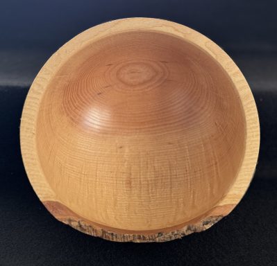 A smooth, round wooden bowl with a light finish and natural wood grain.