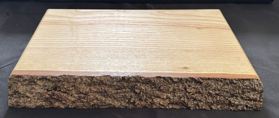 A smooth, rectangular wooden plank with a natural bark edge.