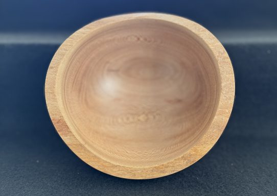 A smooth, light wooden bowl with a rounded shape and natural finish.