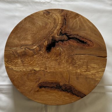 Round wooden platter with natural grain patterns and a polished finish.