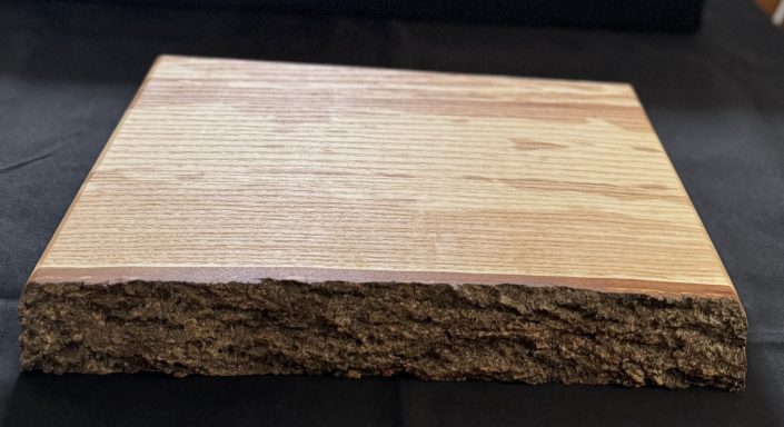 A rectangular piece of wood showing a smooth surface and visible texture on the edge.