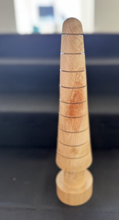 A wooden conical object with horizontal grooves and a rounded base.