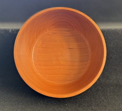 Round wooden bowl with a smooth, polished surface and warm brown tones.