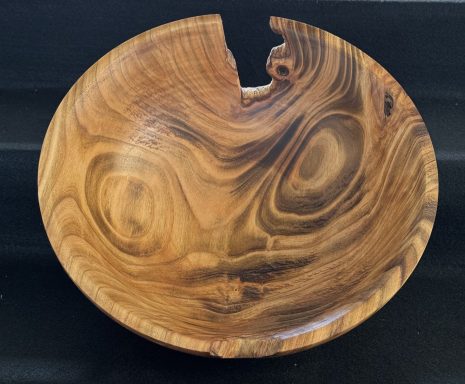 Wooden bowl with a smooth finish and a distinctive cracked edge.