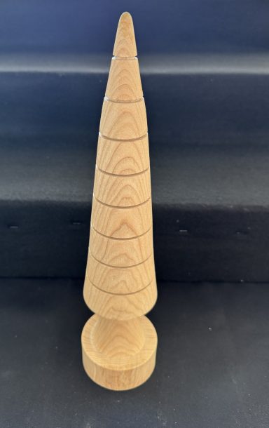 A tall, conical wooden sculpture with engraved geometric patterns.