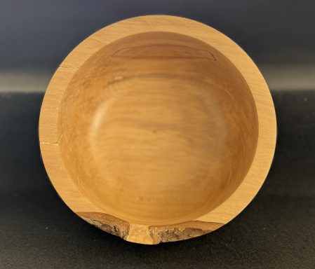 A smooth, round wooden bowl with a natural finish and subtle grain patterns.