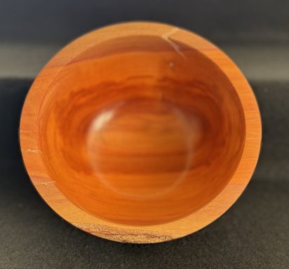 A smooth, wooden bowl with a warm, reddish-brown finish and a rounded interior.