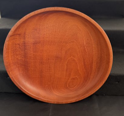 Round wooden plate with a smooth surface and rich brown colour.