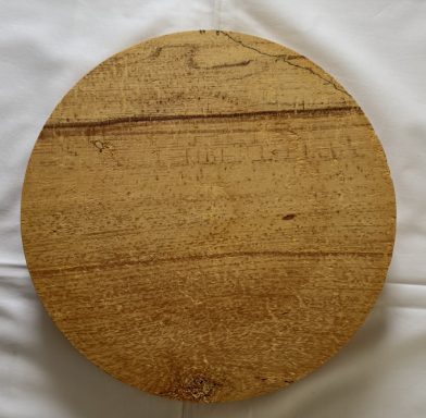 Round wooden board with a smooth surface and natural grain pattern.