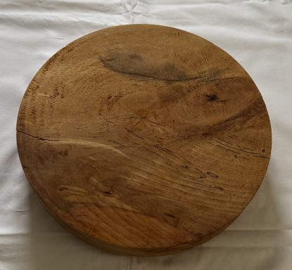 Round wooden cutting board with a smooth surface and natural grain.