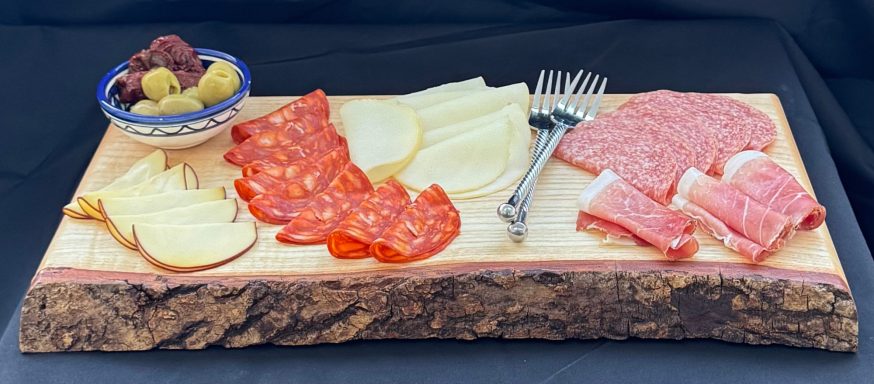 Charcuterie board with assorted meats, cheeses, olives, and a small fork.