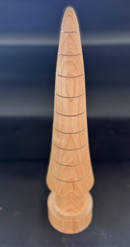 Carved wooden sculpture with a tapered, elongated shape and subtle grooves.