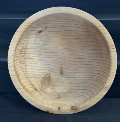 A smooth, round wooden bowl with a light finish and visible wood grain patterns.